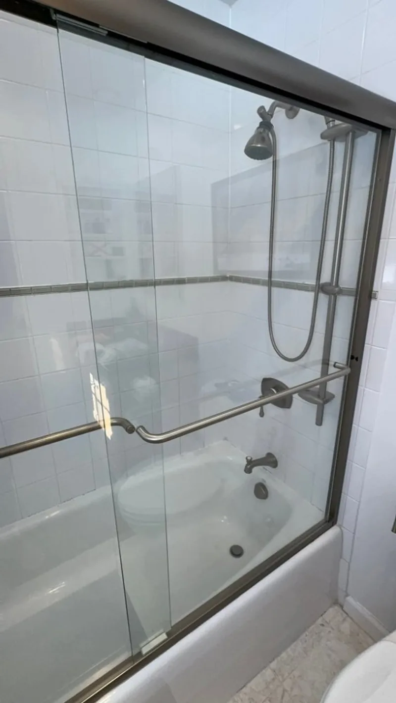 Glass bathtub enclosure and chrome shower fixtures after cleaning