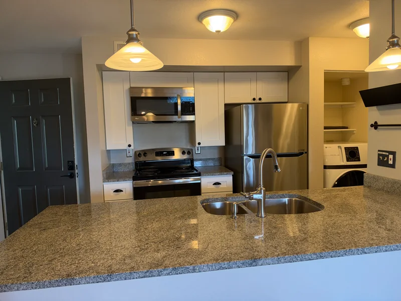 Clean kitchen with granite counters, a double sink and stainless steel appliances